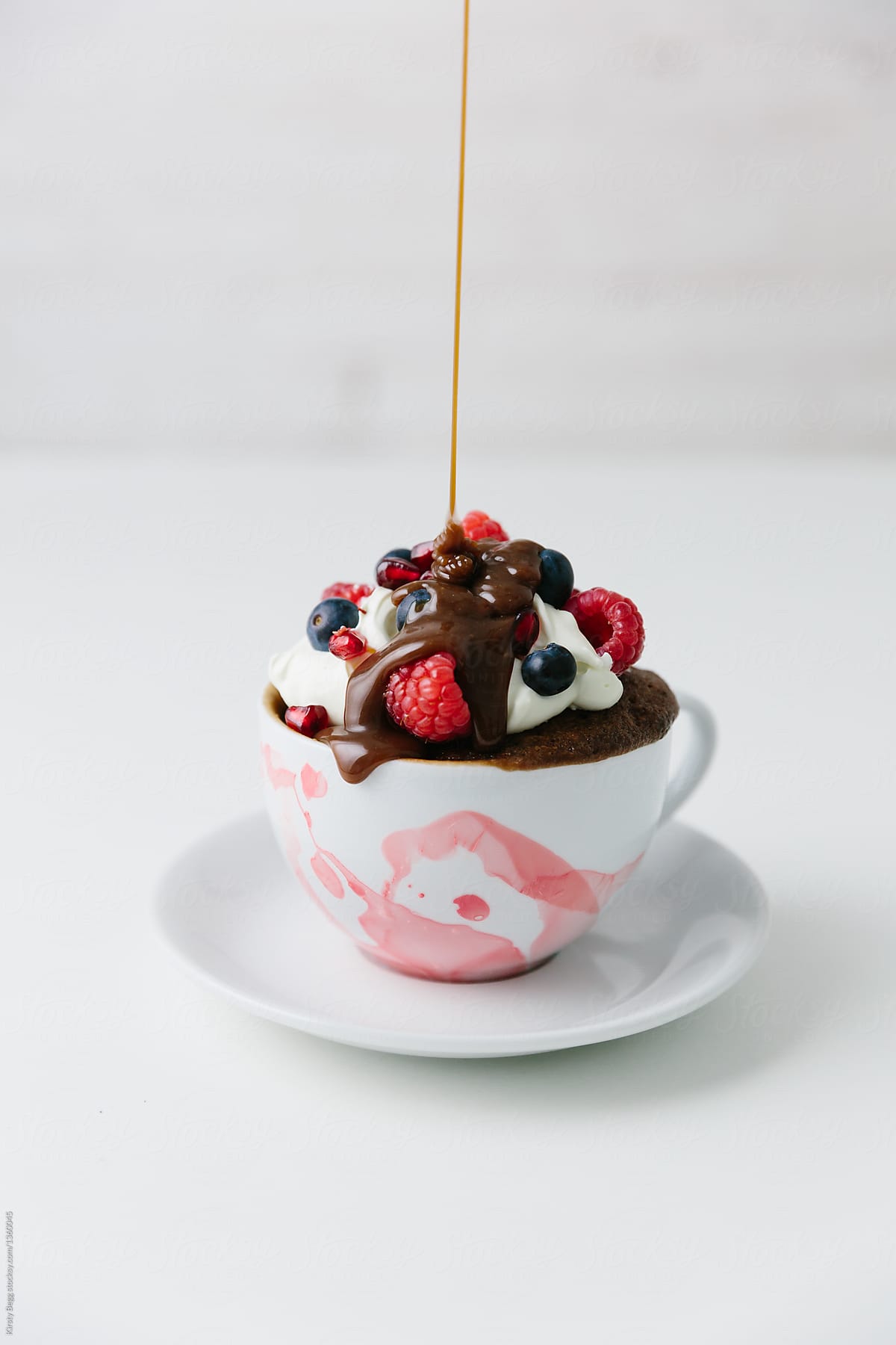 Chocolate drizzled over mug cake dessert with cream and berries