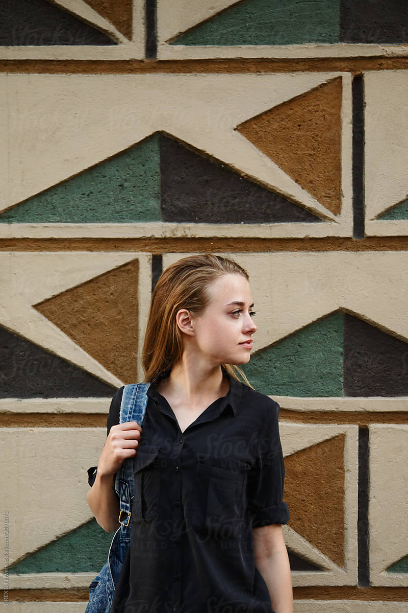 Woman with backpack at pattern wall