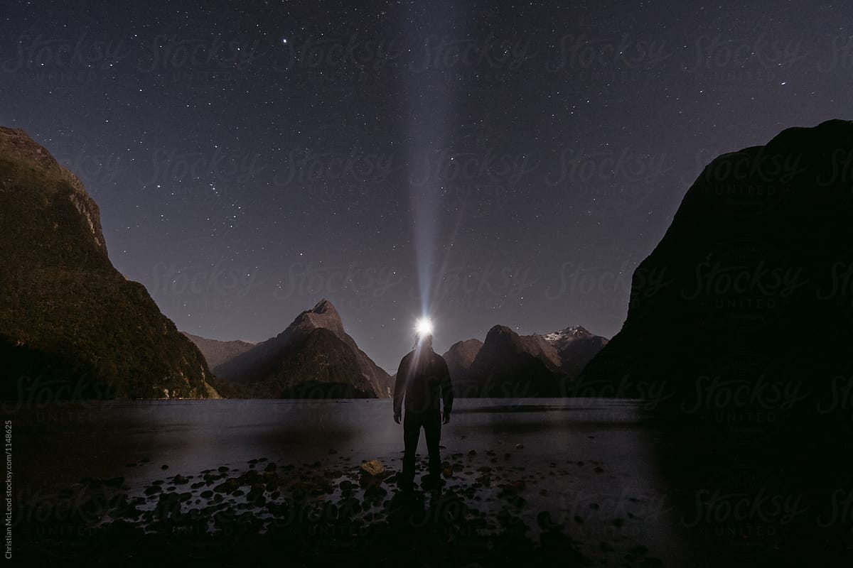 man hikes at night in a fjord