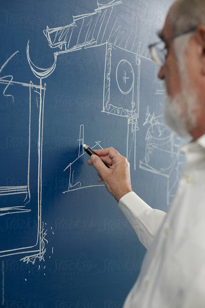 Mature professor drawing on a blue chalkboard