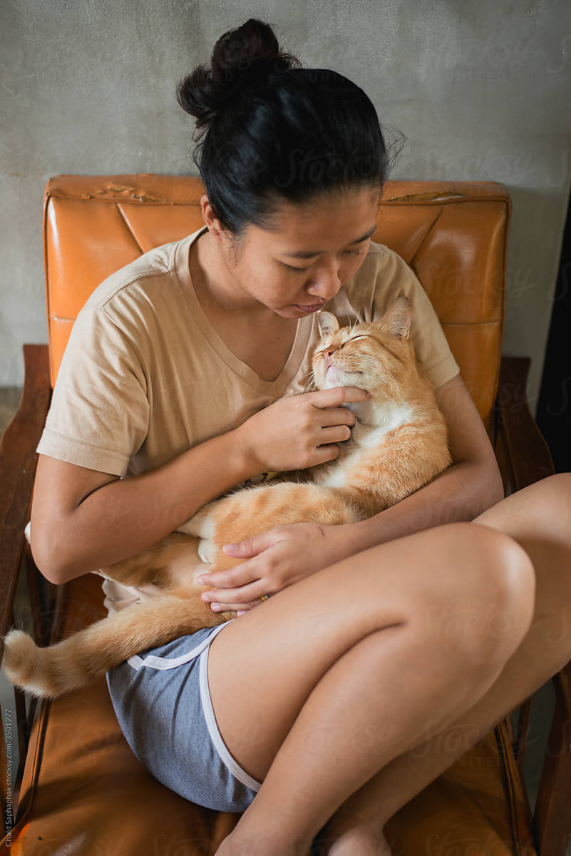 Asian woman hugging orange cat