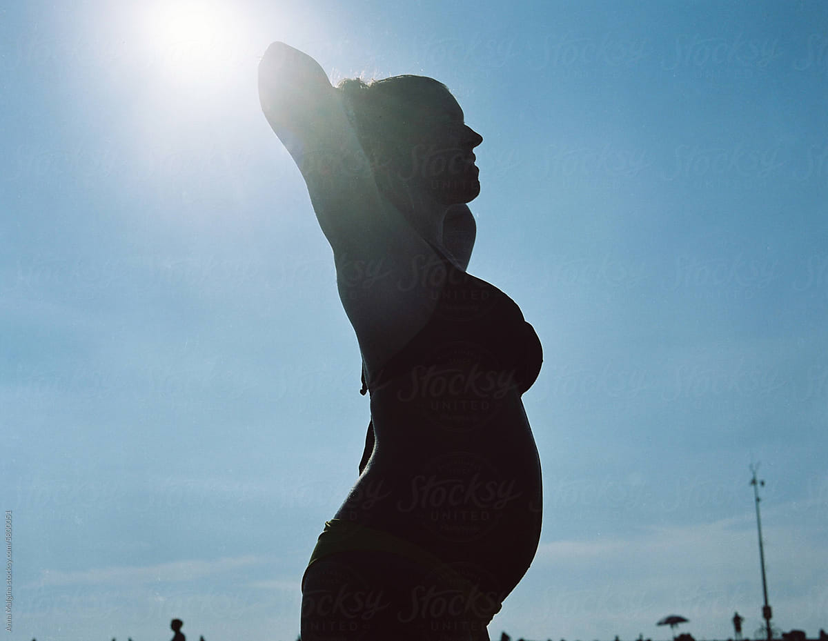 A happy pregnant woman silhouette in a swimsuit