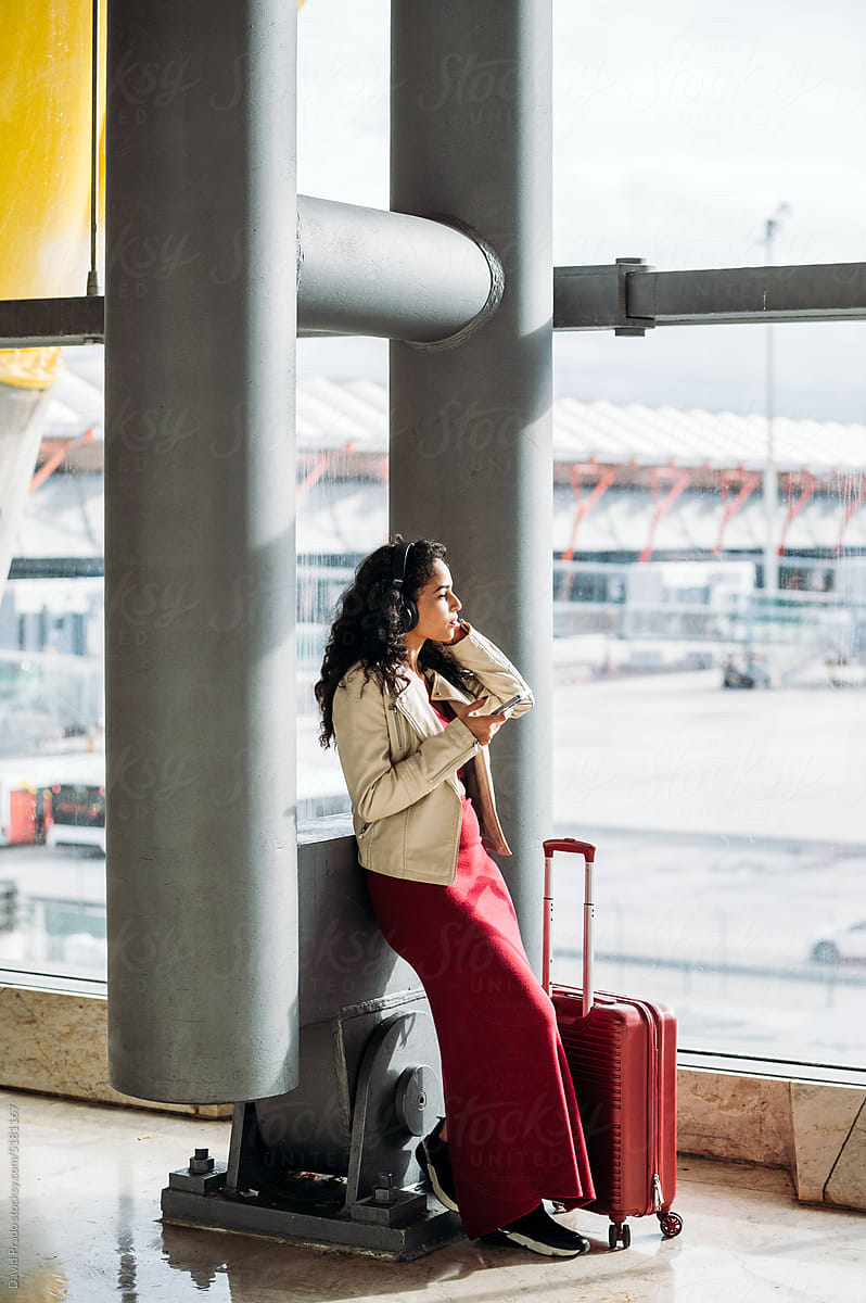 Woman with luggage listening to music in airport