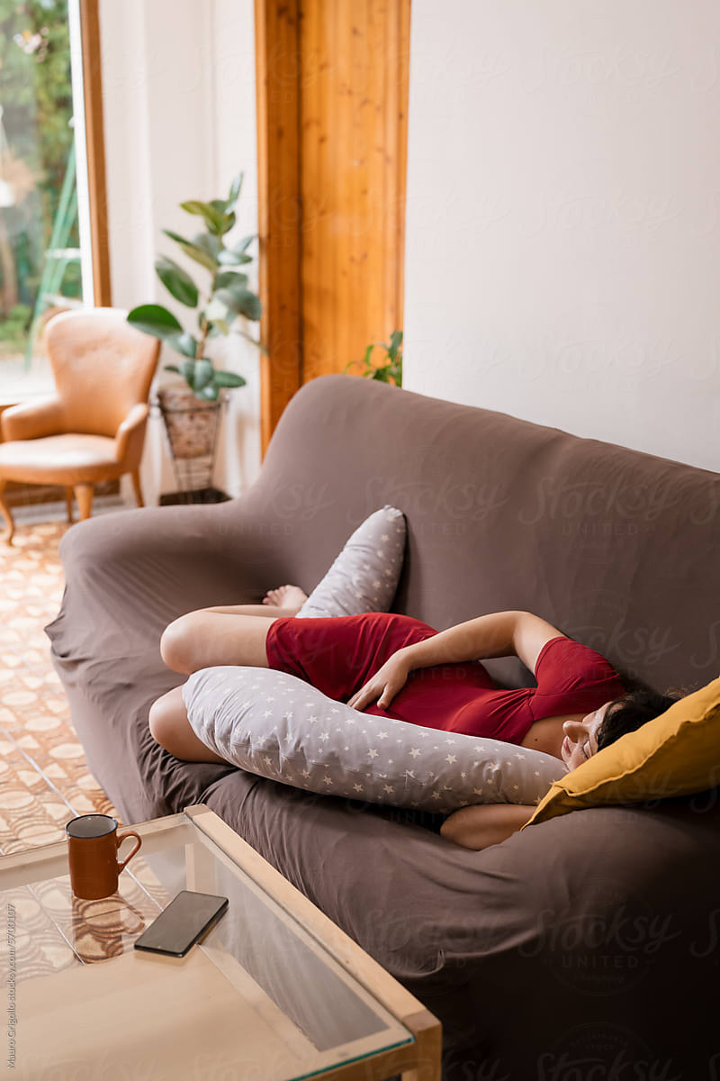 A pregnant woman lying on the sofa at home