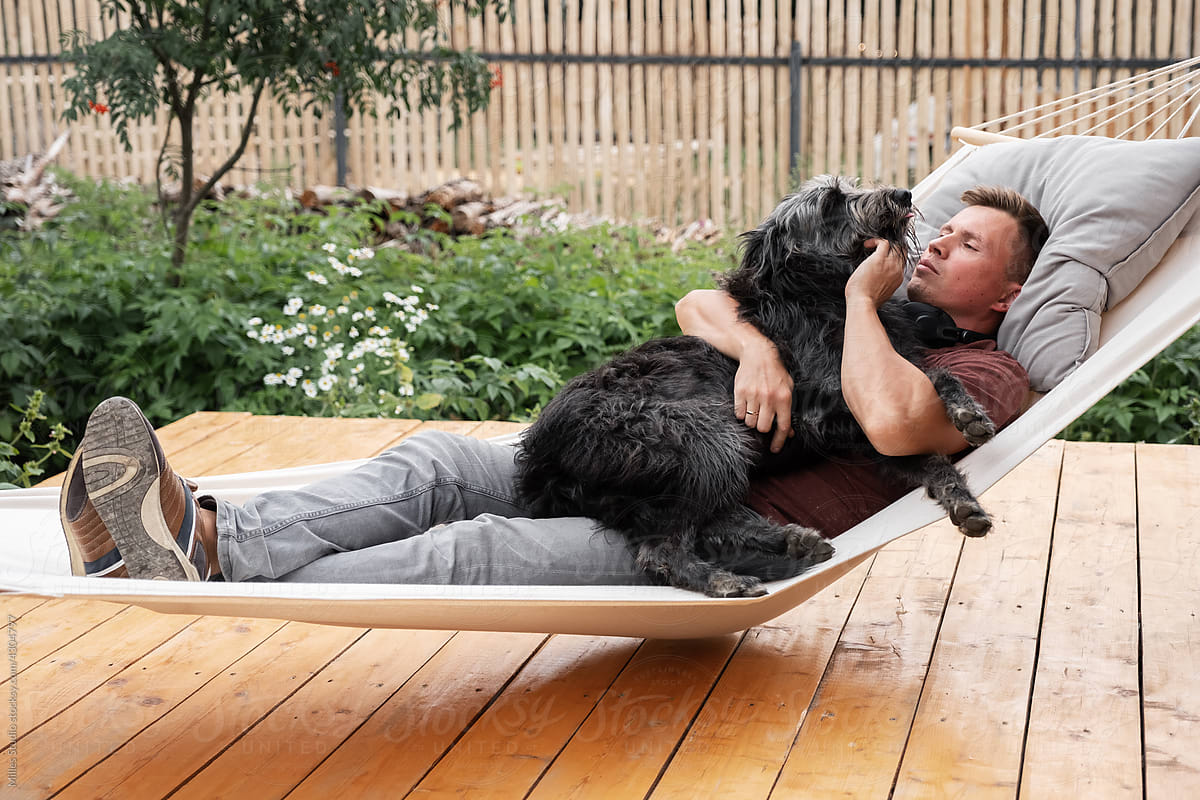 Male owner hugging dog in hammock