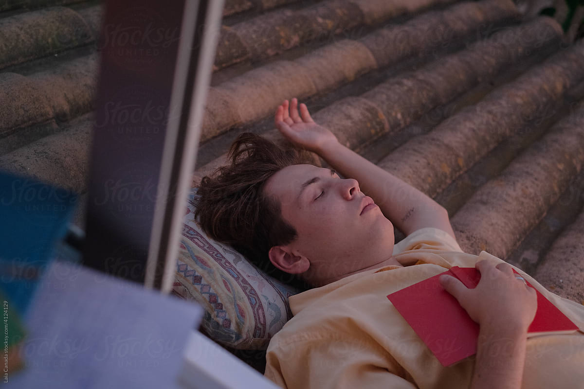 Young student laying on his back holding a book