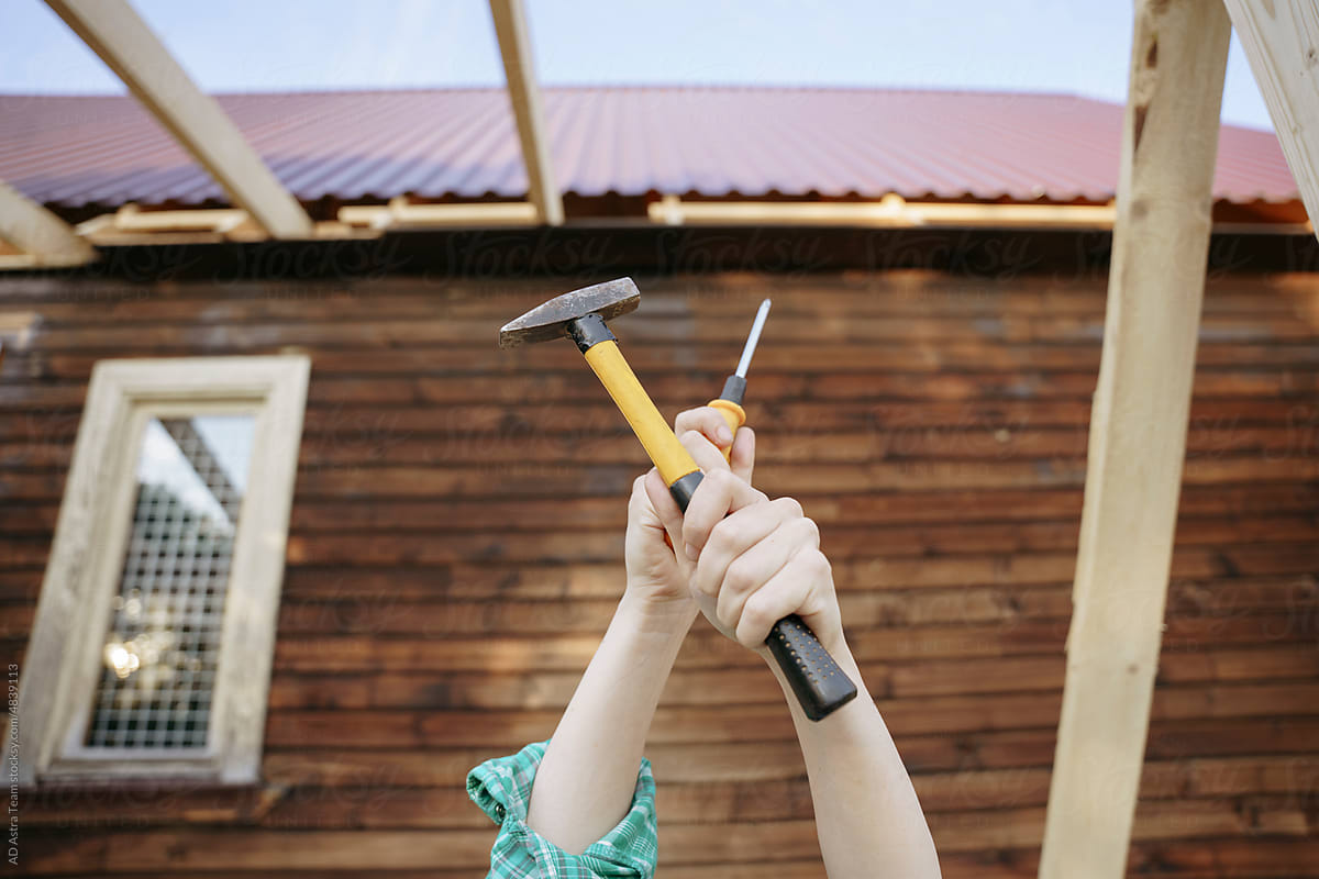 The woman\'s hands hold a hammer and a screwdriver