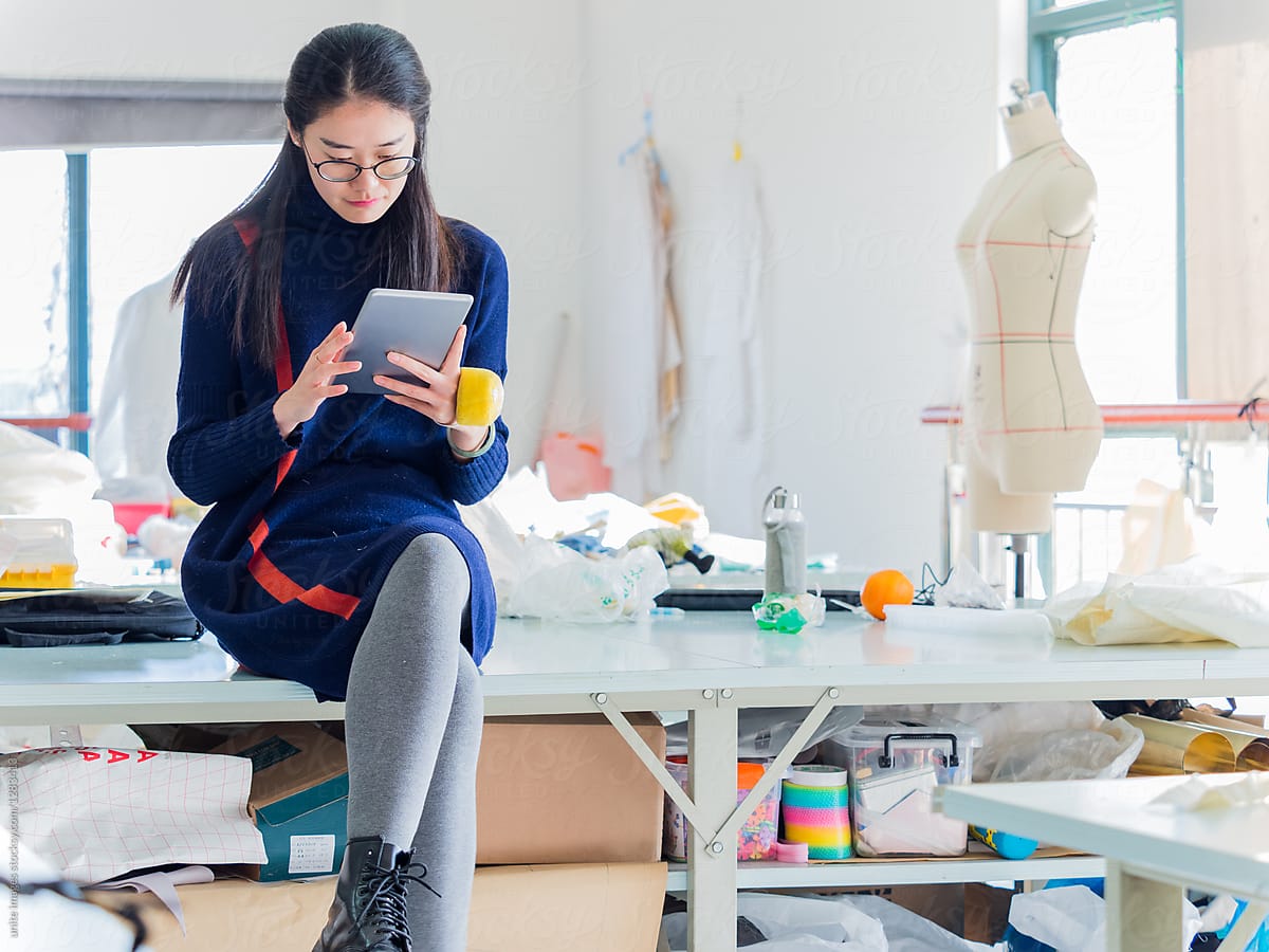 fashion dressmaker using digital tablet in studio