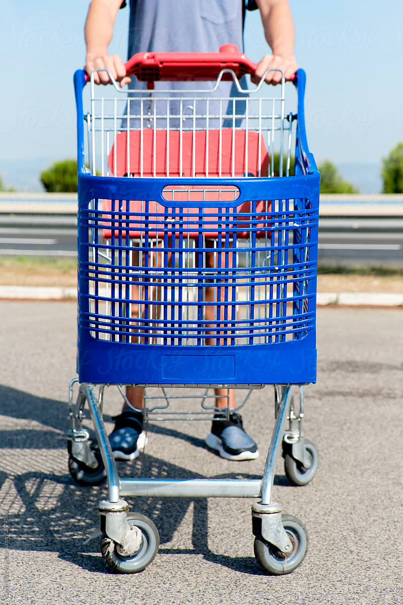 young man pushing an empty shopping cart