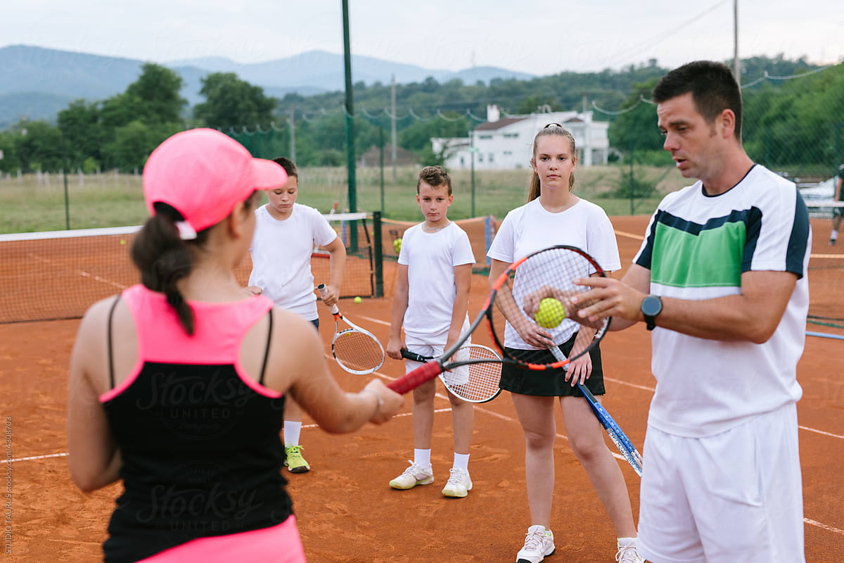Coach teaching kids the basics of the tennis