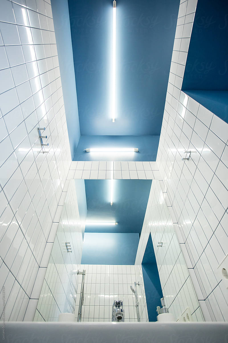 Blue toilet with white tiles and geometric lamps