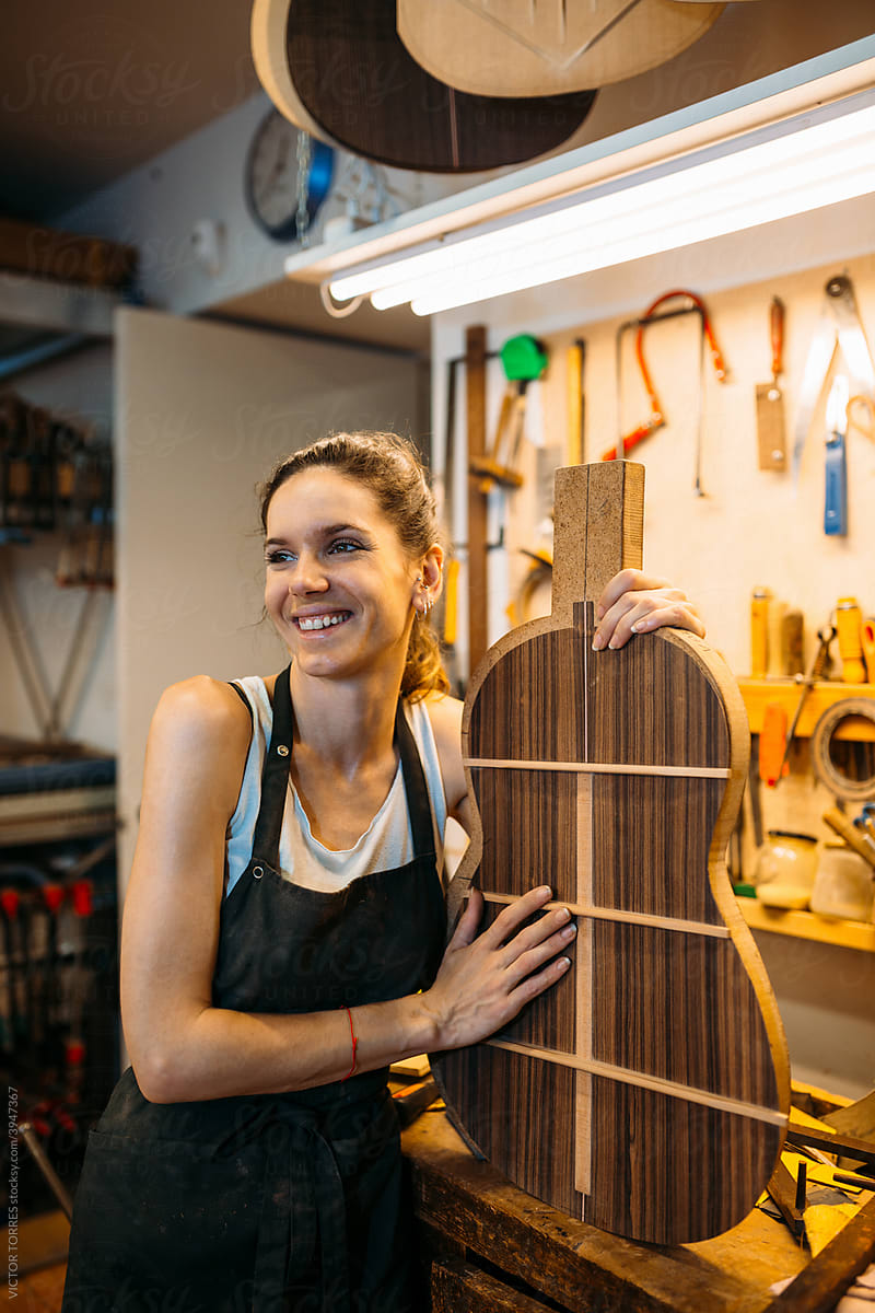 Young Woman Luthier holding a guitar template