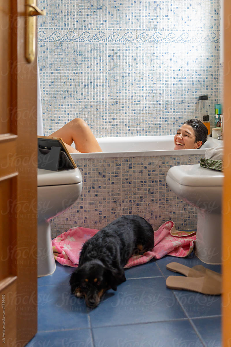 Girl Taking A Bath And Watching Online Series Next To Her Little Dog.