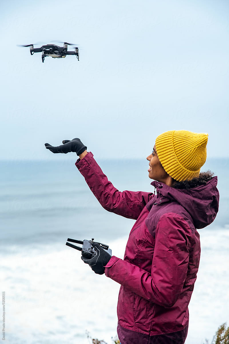 black woman tourist operating drone above ocean