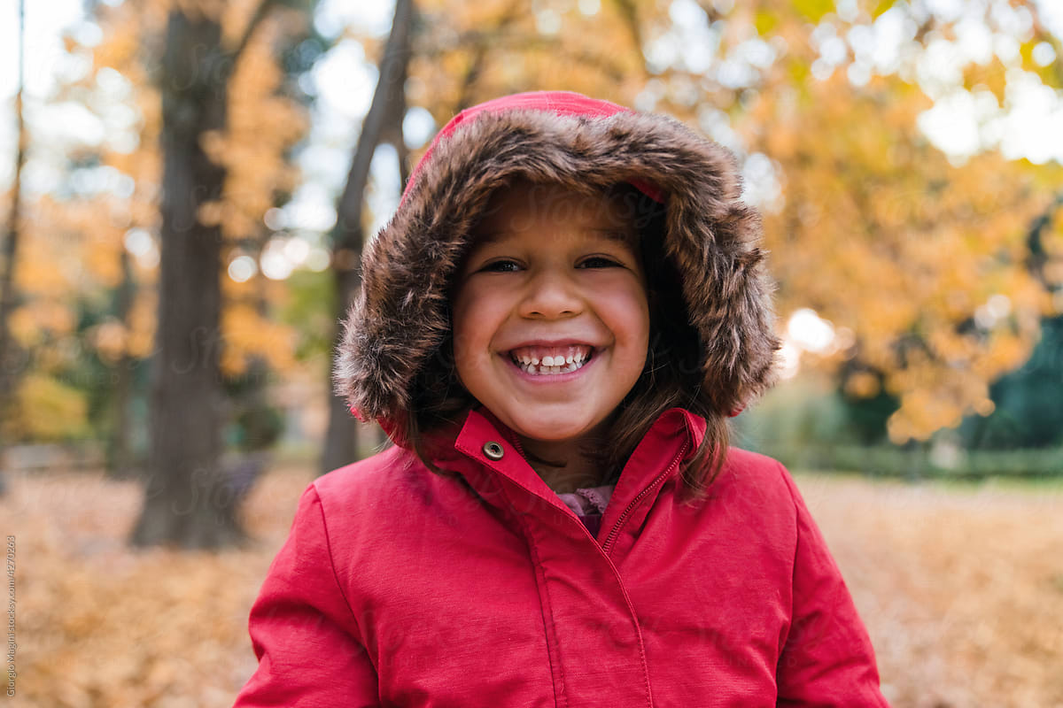 Smiling Little Girl with Red Jacket in Autumn Park