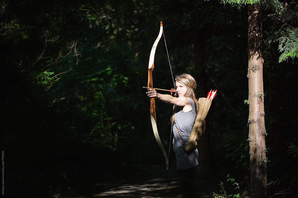 Woman aiming with archery in the wood