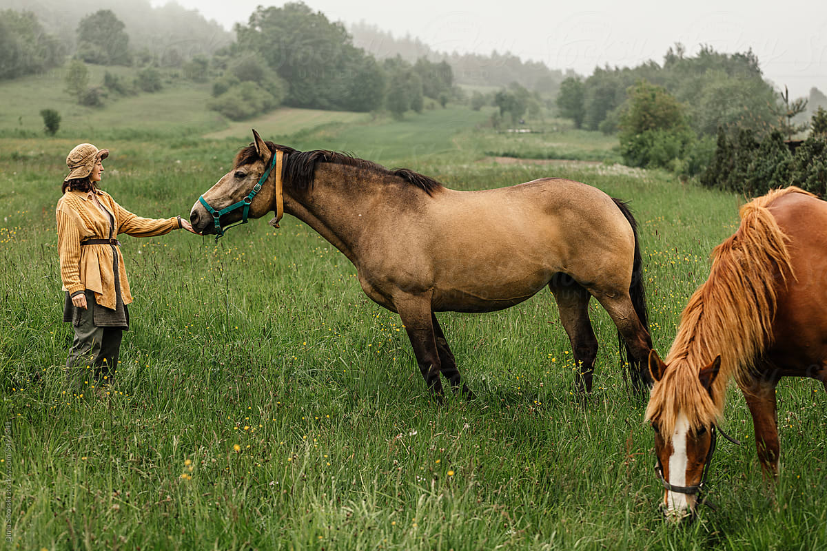 A farmer strokes his horse on a picturesque ranch