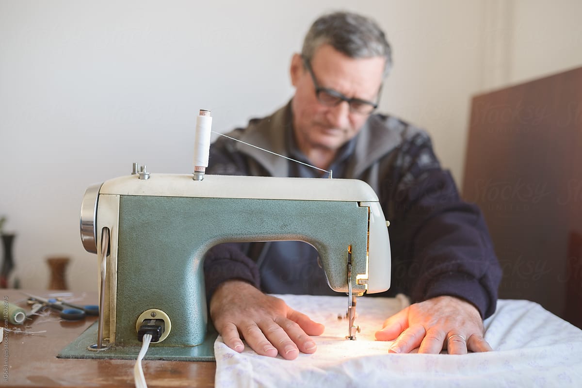 Male Dressmaker Using Sewing Machine by Stocksy Contributor