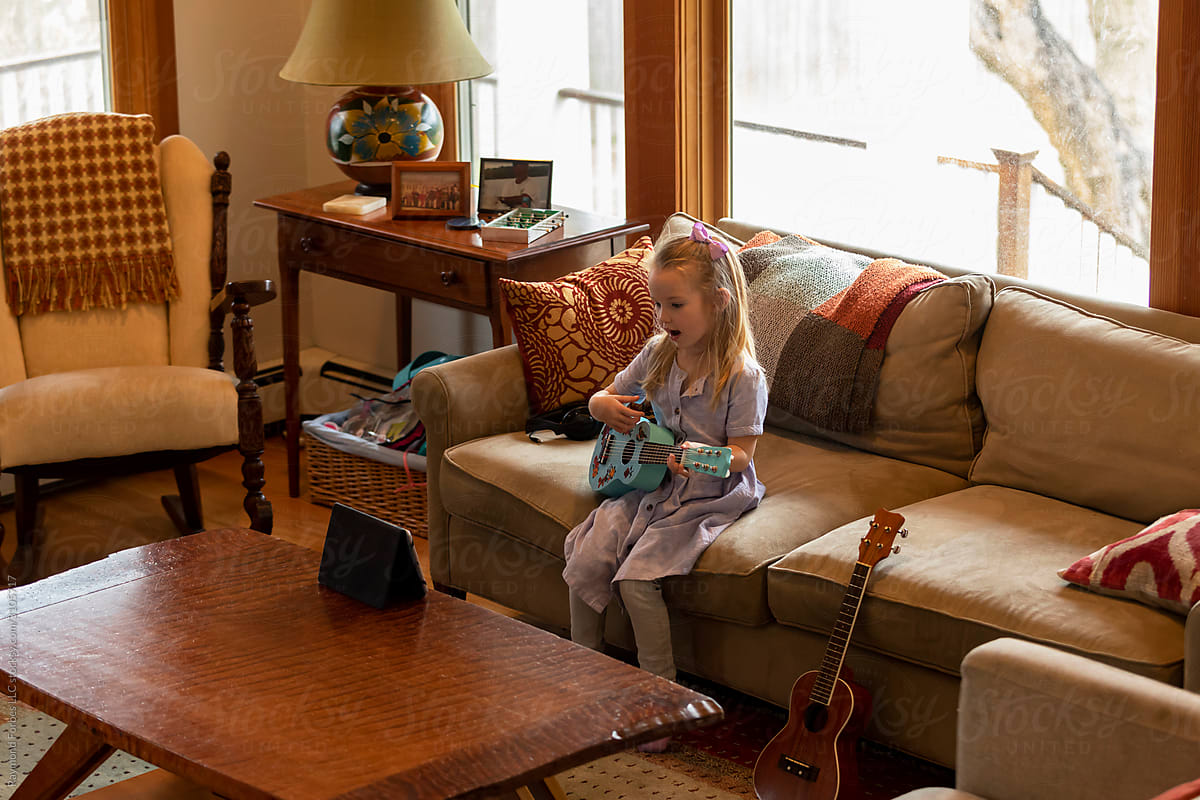 Young Child Learning to play Guitar Video Video Chat sitting in Living Room