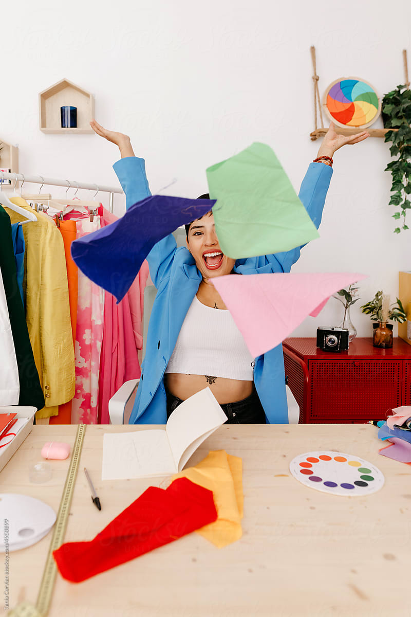 Excited fashion designer throwing colorful fabric