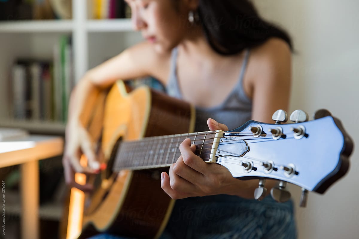 Closeup of guitar neck while woman plays