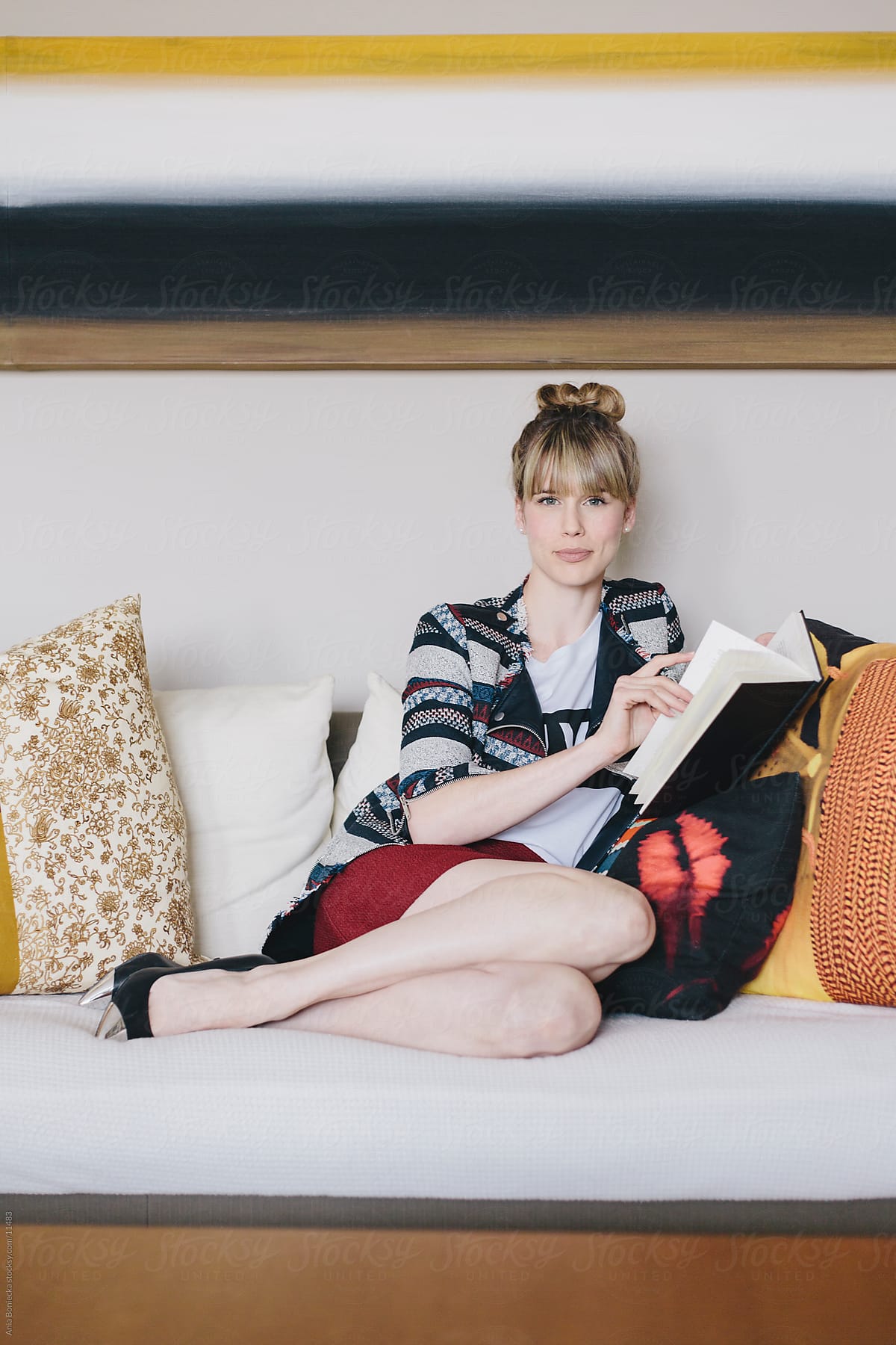 A Beautiful Blonde Reading A Book On The Sofa By Stocksy Contributor