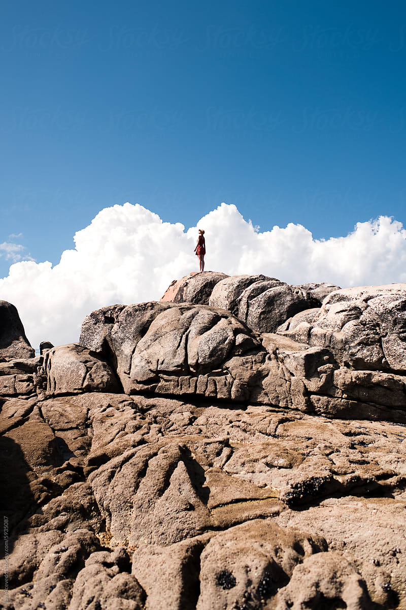 Female silhouette on mountain top with big clouds