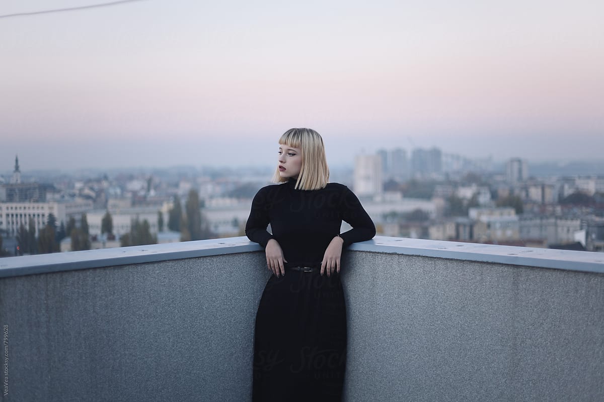 Portrait of a stylish blonde woman on the roof of the building during sunset