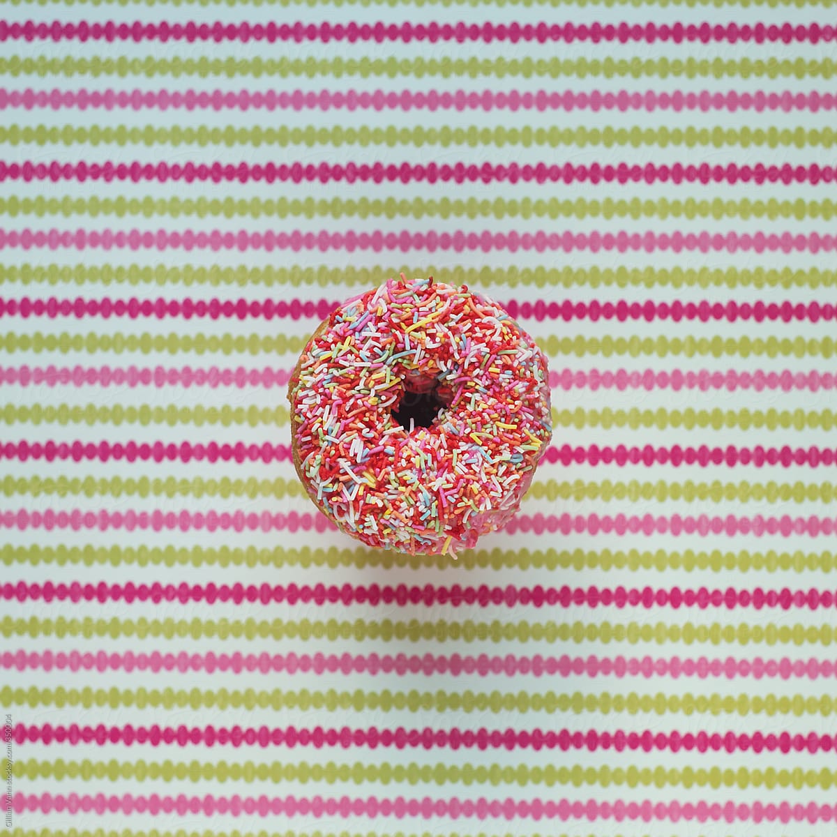 sweet iced donut with sprinkles on a striped background