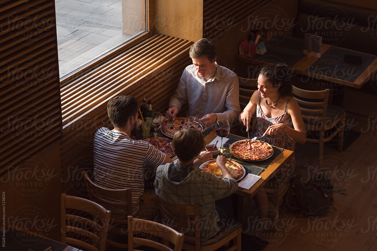 Group of friends eating pizza in a restaurant