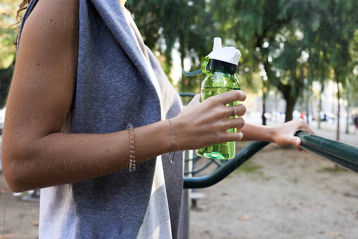 Sportswoman crop green bottle water eliptic machine.