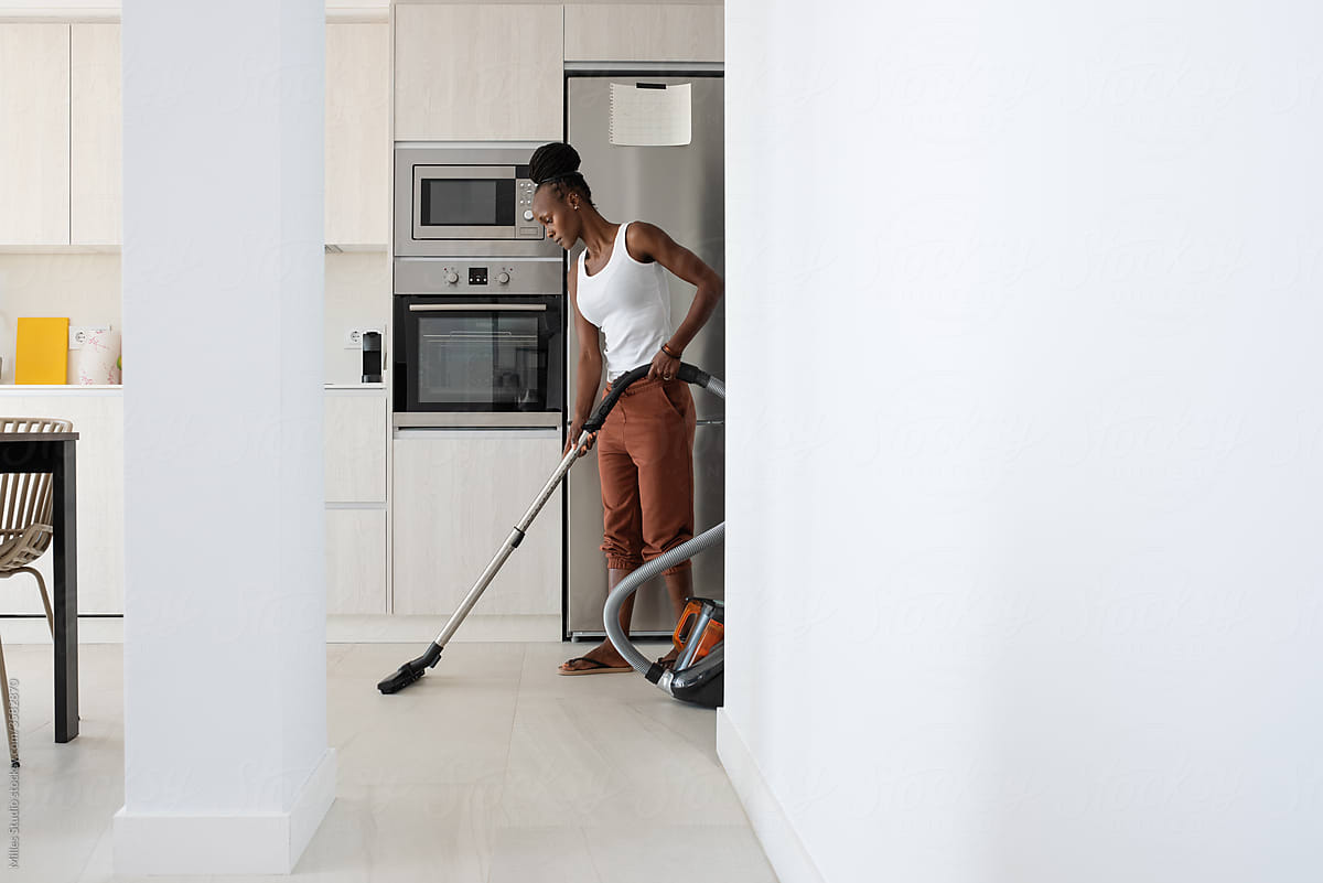 African housewife tidying floor in kitchen