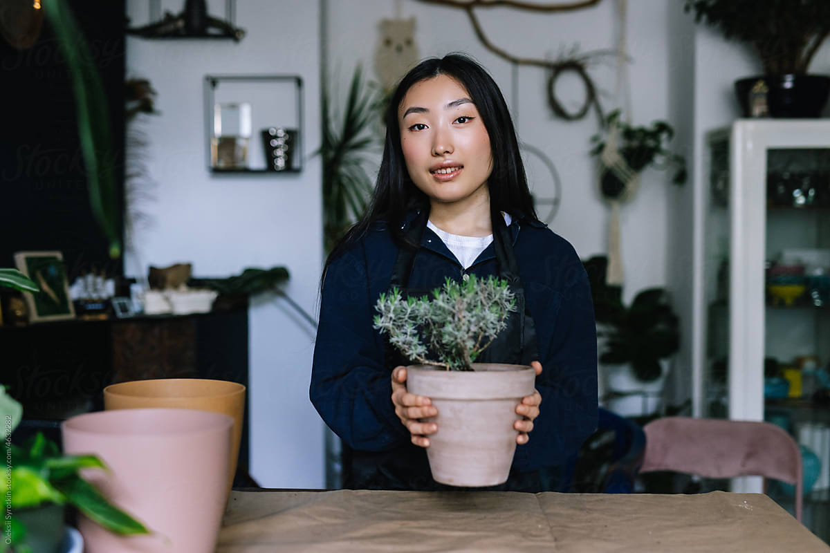 Saleswoman posing with houseplant at working space