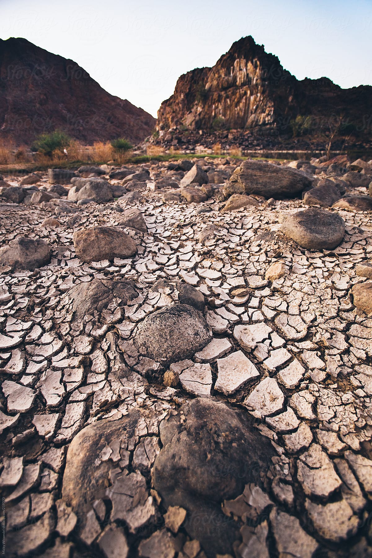 cracked mud and boulders in a dried out river bed