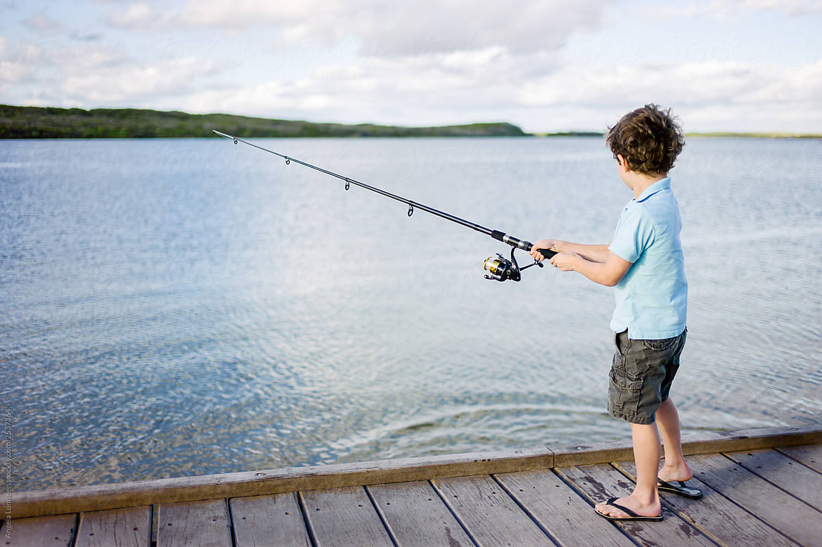 Boy standing with a fishing rod on a wooden dock