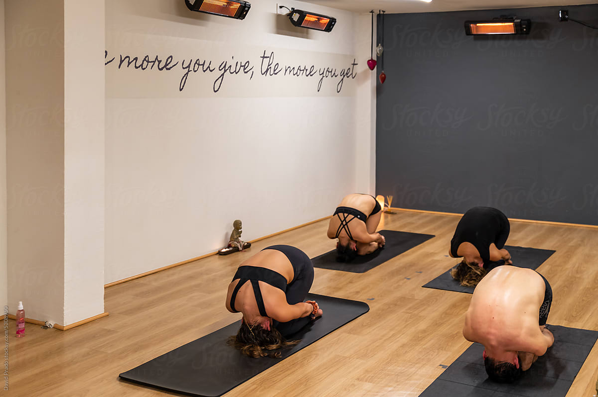 People practicing stretching pose bikram yoga in health club
