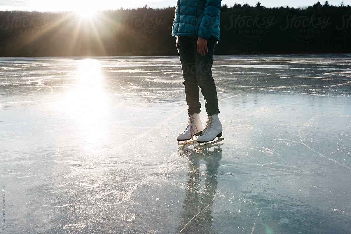 young woman standing on a frozen lake with skates