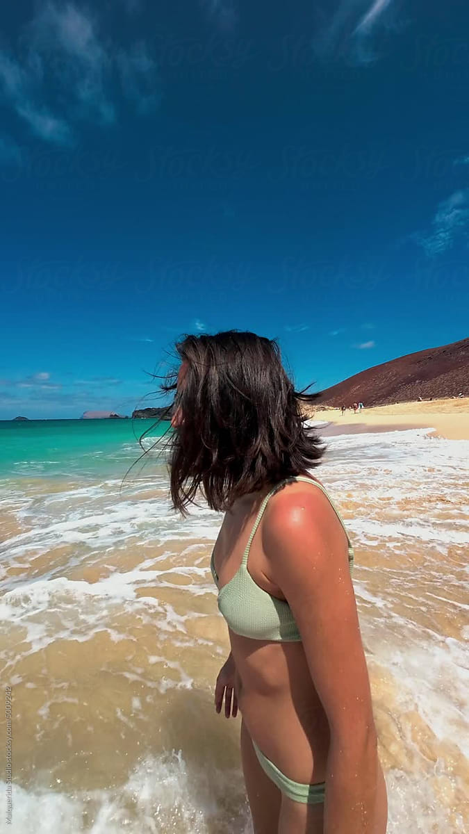 pov-young-woman-splashing-to-camera-on-beach-by-stocksy-contributor