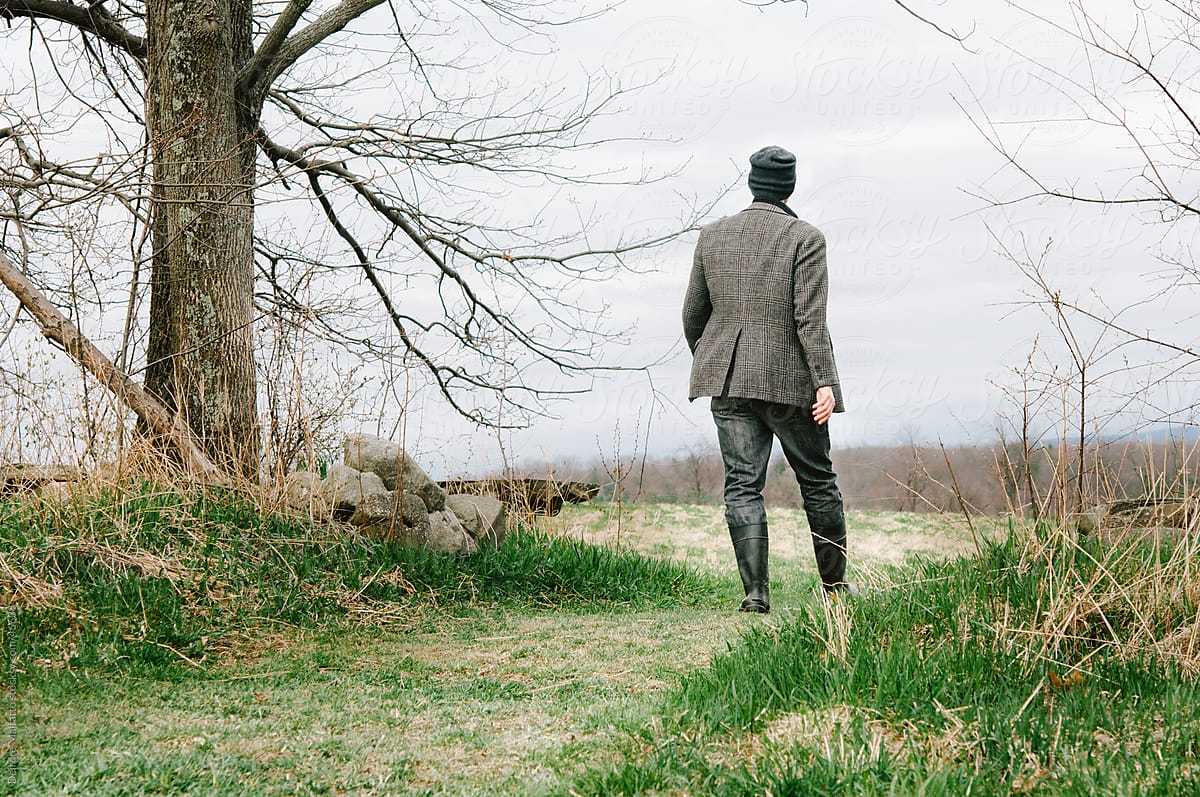 Back of man walking through woods, from behind