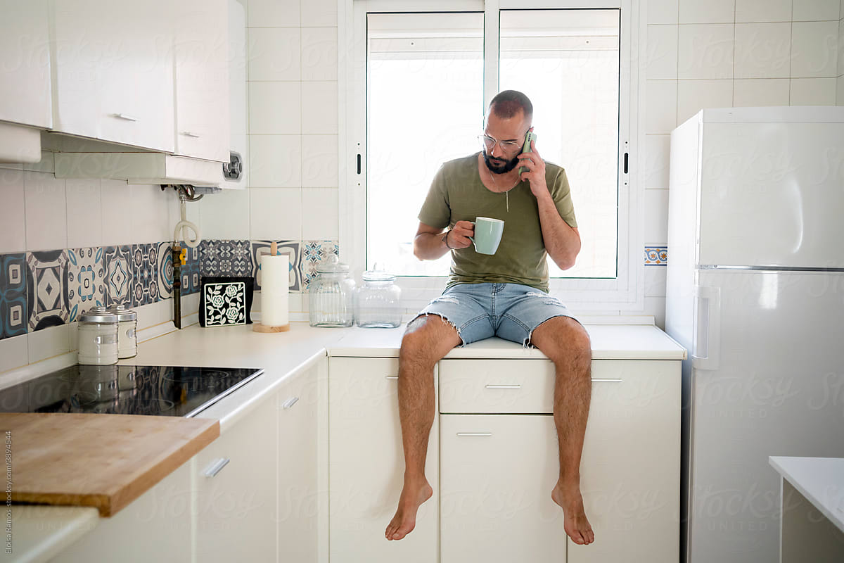Hipster man talking by phone at kitchen