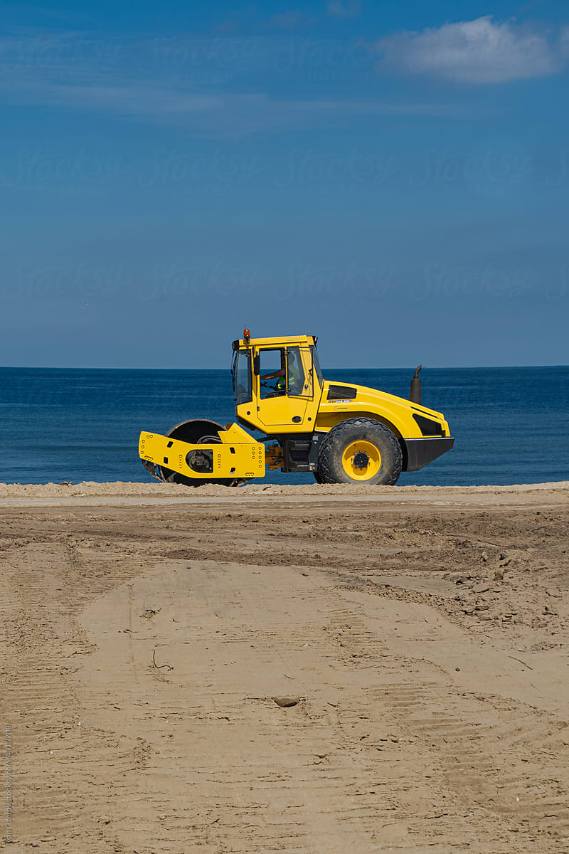 Yellow soil compactor on beach