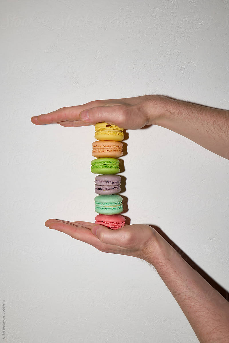 Anonymous hand stacks macaroons on the white background