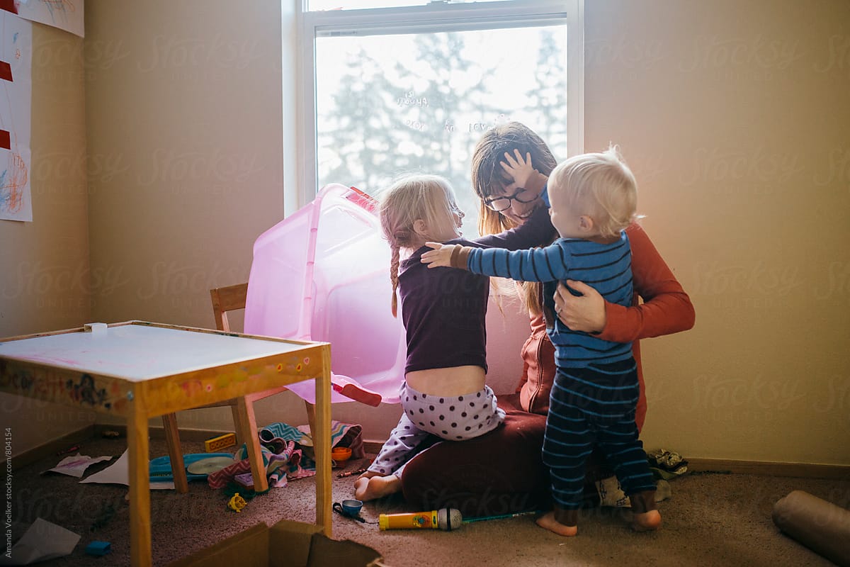 Mother and Children play and hug in a messy room