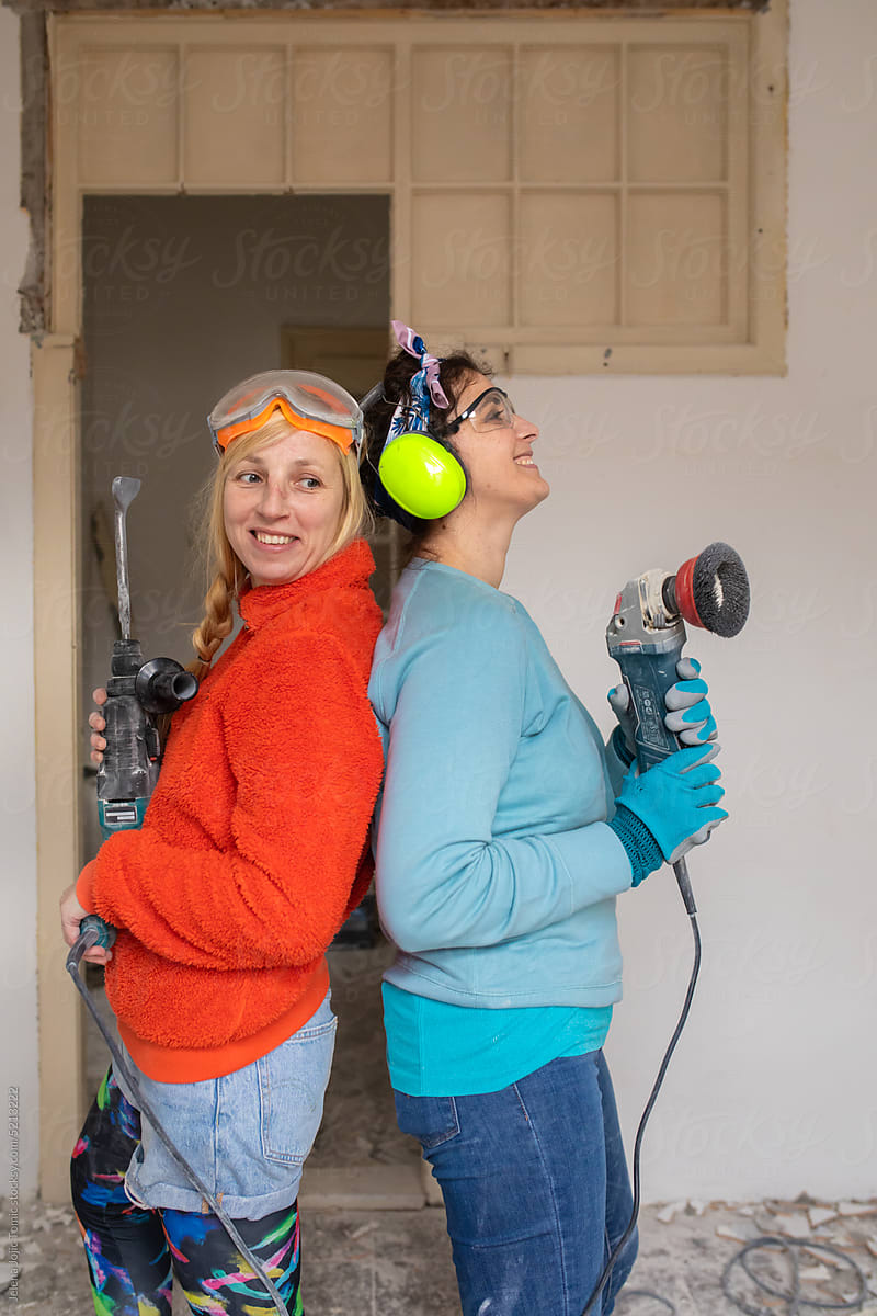 Funny, smiling portrait of two women excited about home renovation