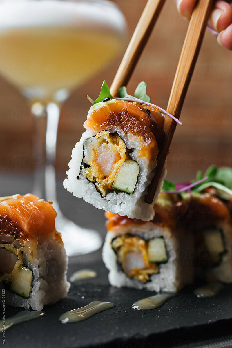 Sushi Rolls being Held By ChopSticks