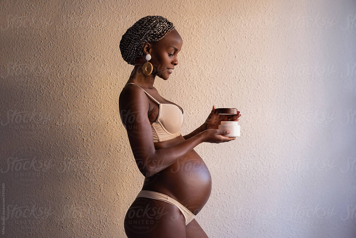 Black pregnant woman opening skin care product