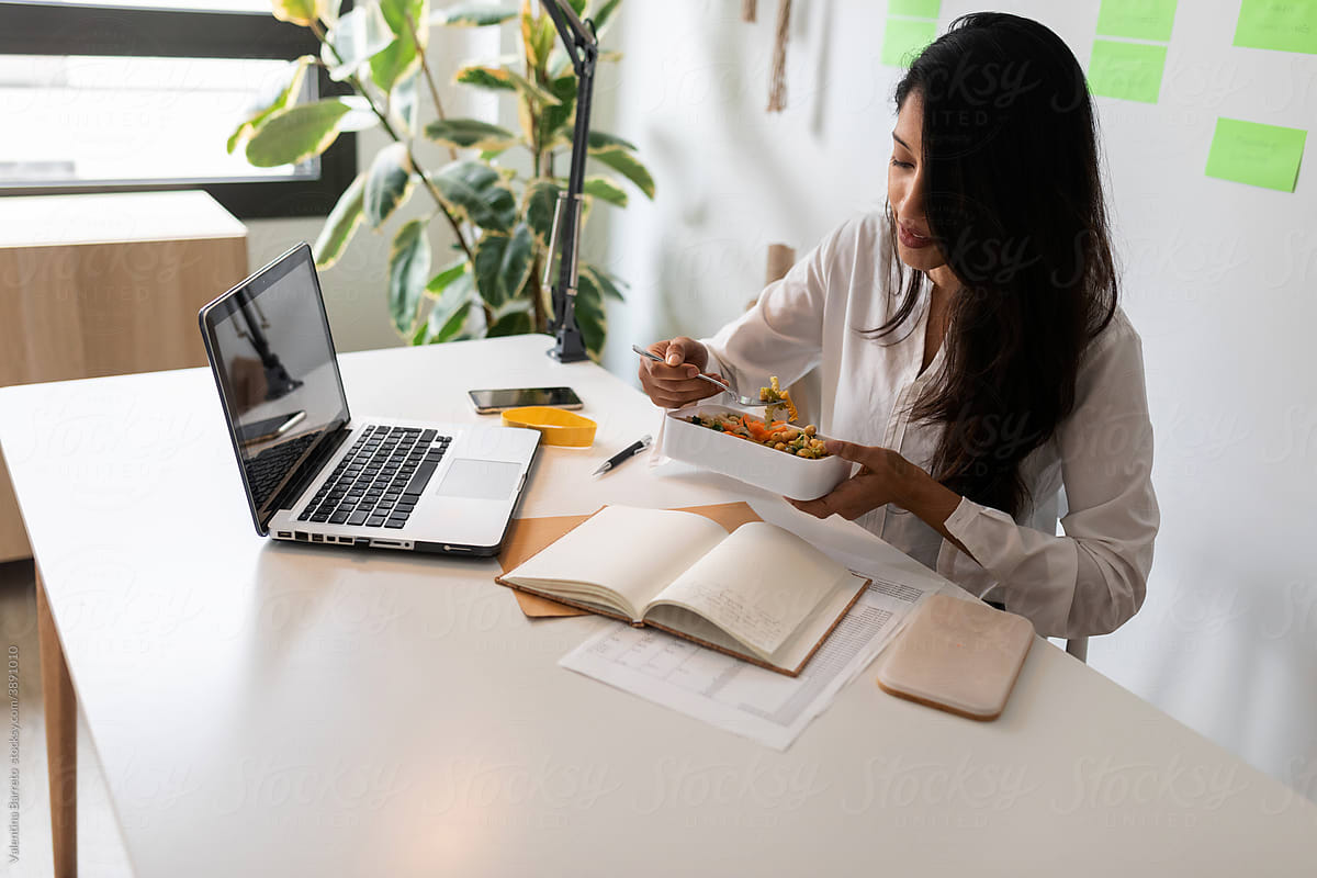 Brunette woman eating salad at office