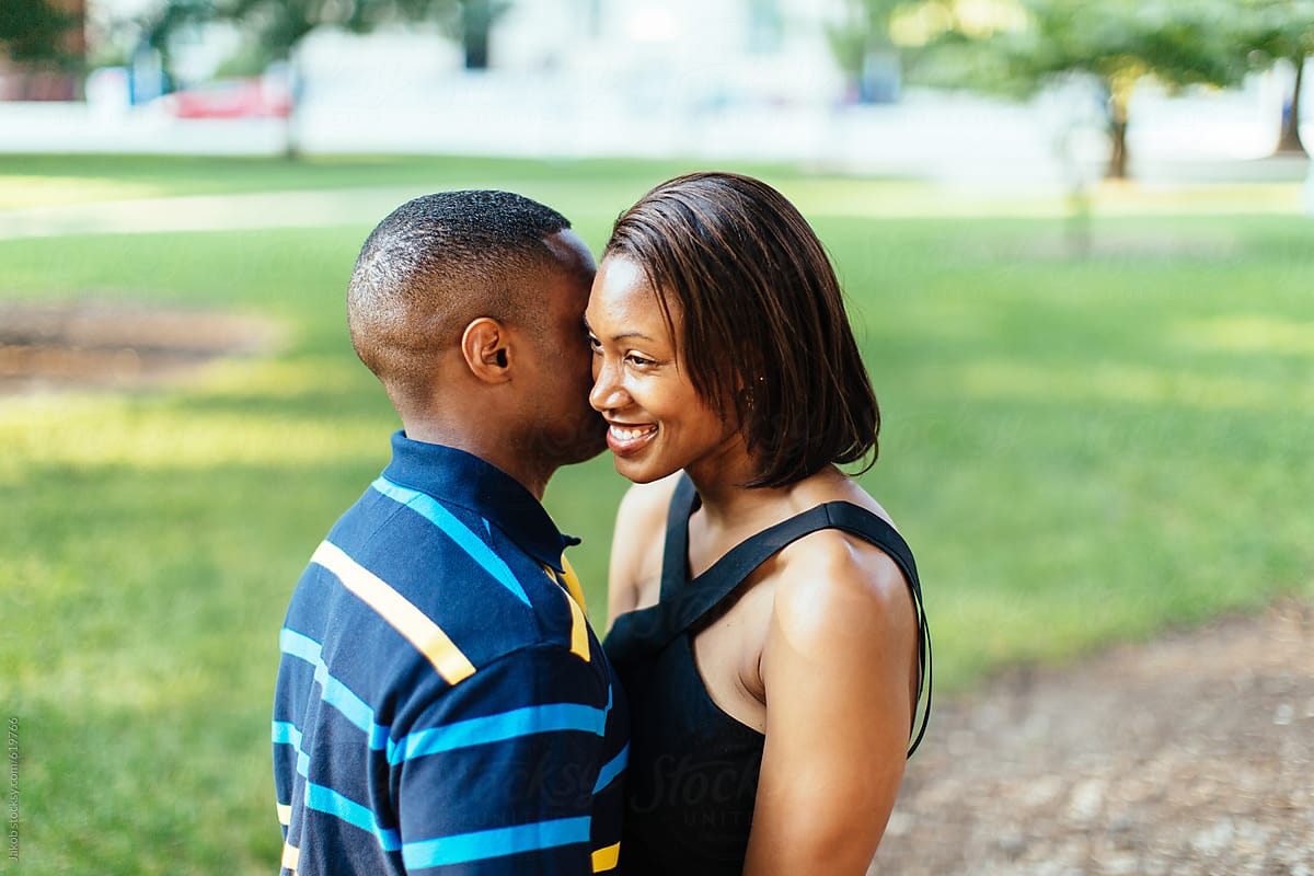 African-American male whispering into his girlfriend\'s ear
