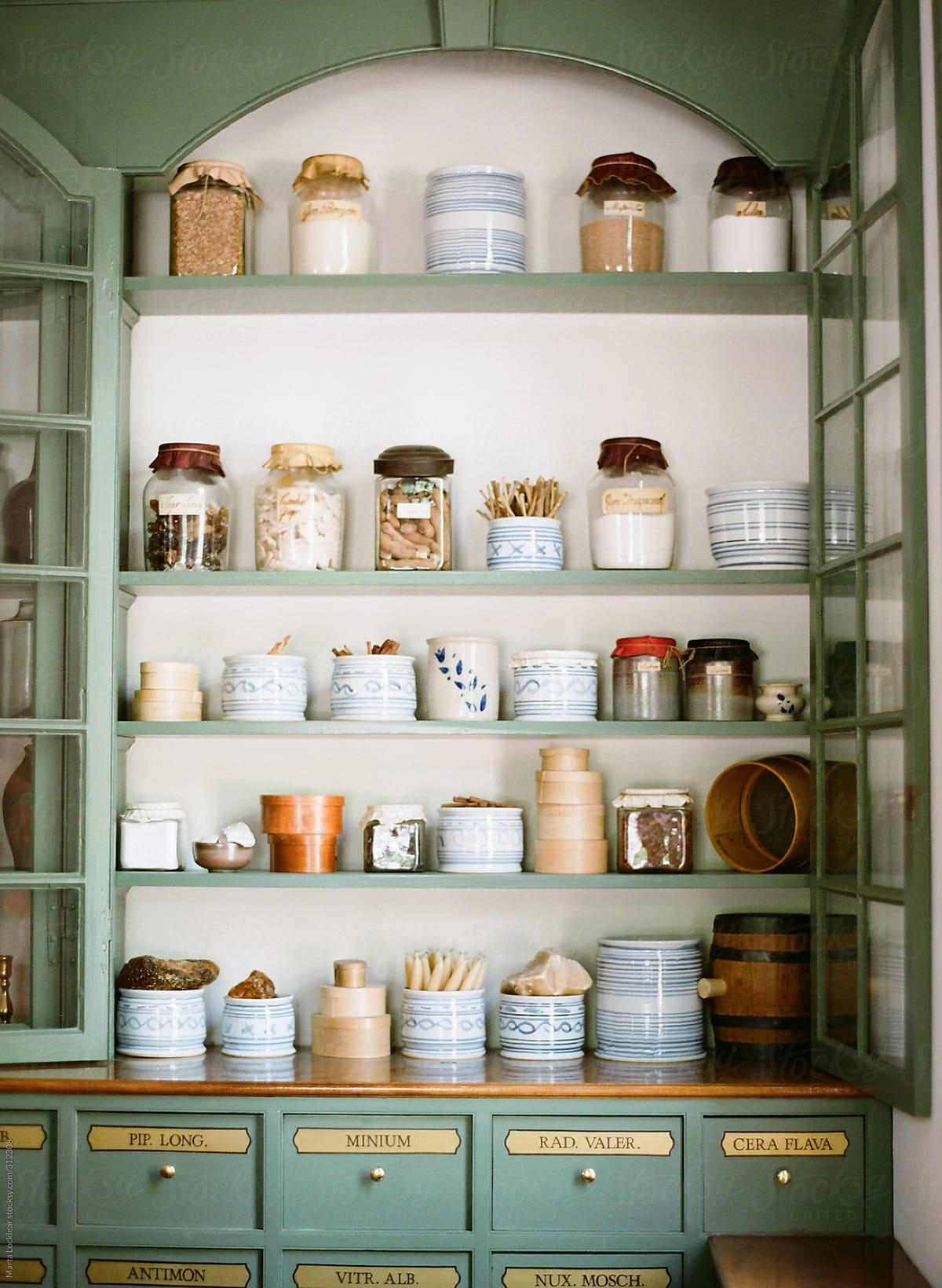 Historic colonial apothecary jars on old green wooden shelves