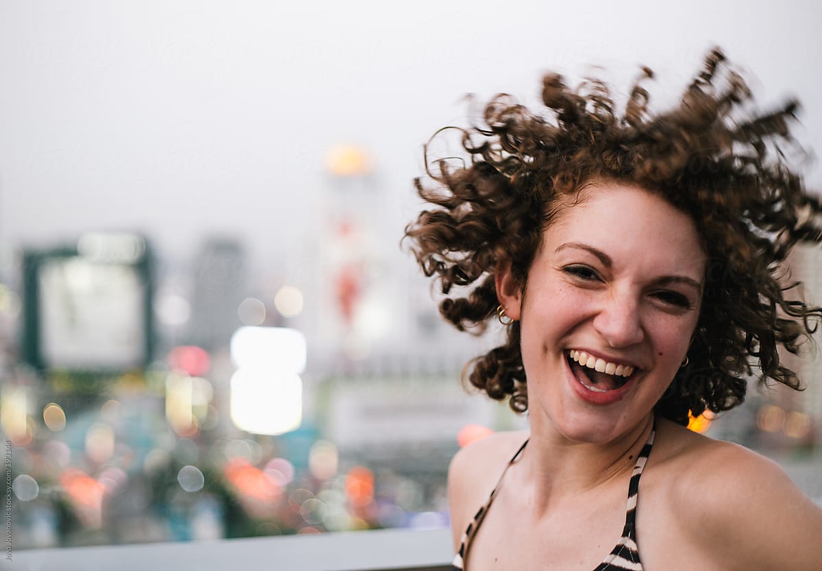 Happy young woman with curly hair jumping of joy